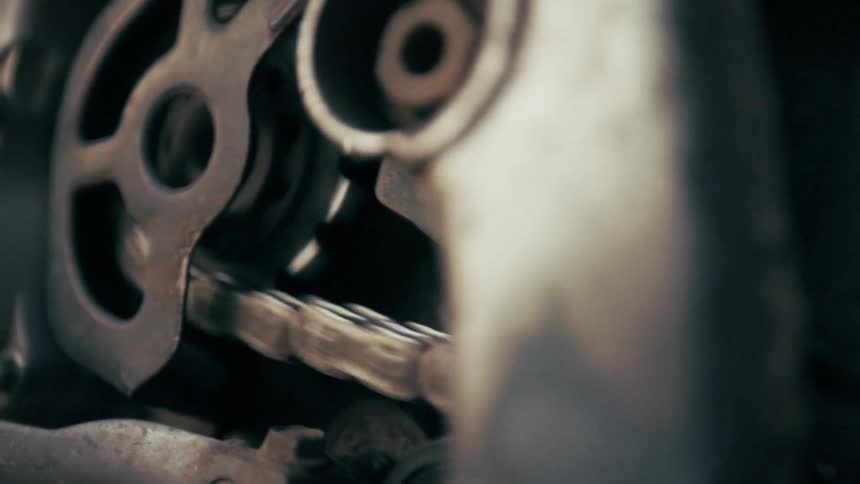 Closeup of a metal chain and gears moving on industrial machinery