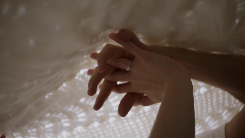 A woman rubs her hands on lace sheets