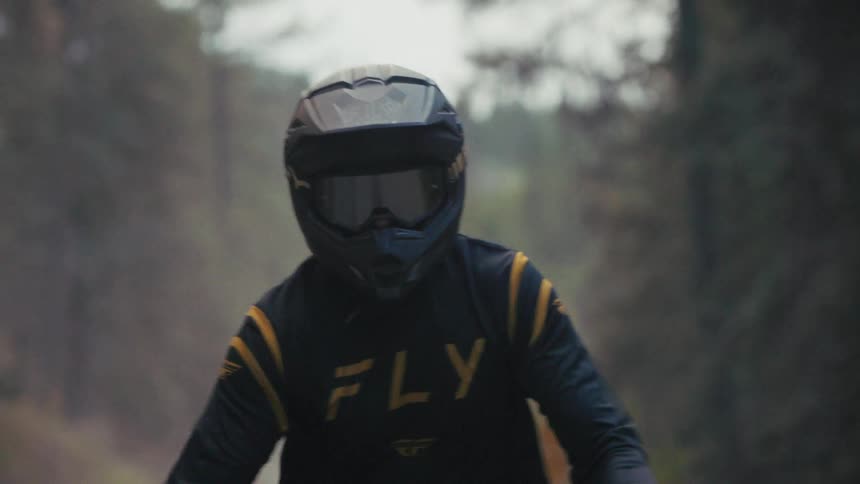 Motocross rider wearing a fullface helmet while moving along a trail with a blurred background