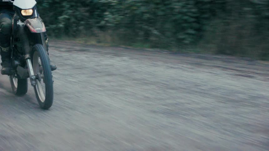 Motocross rider cornering on a dirt road with dust being kicked up
