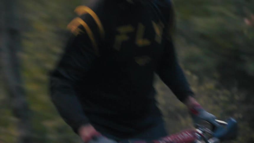 Cyclist riding a motorbike on a rural dirt road through woodland