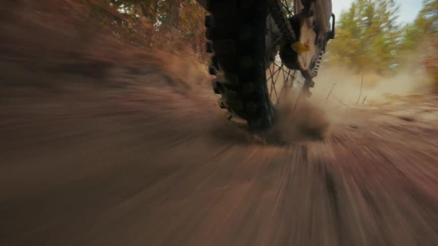 Rear motorcycle tire kicking up dirt while moving on an offroad trail