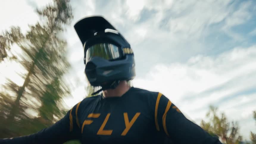 Biker wearing a helmet riding a motorcycle in a road surrounded by trees outdoors during day time