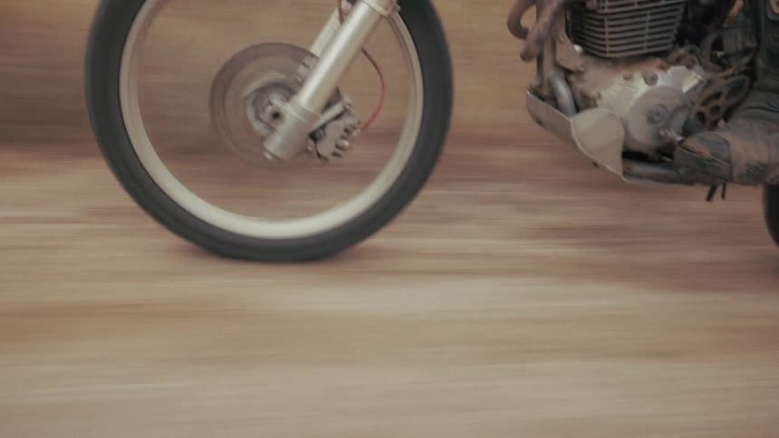 Front wheel and engine of a motorcycle in motion on a dirt trail with speed blur