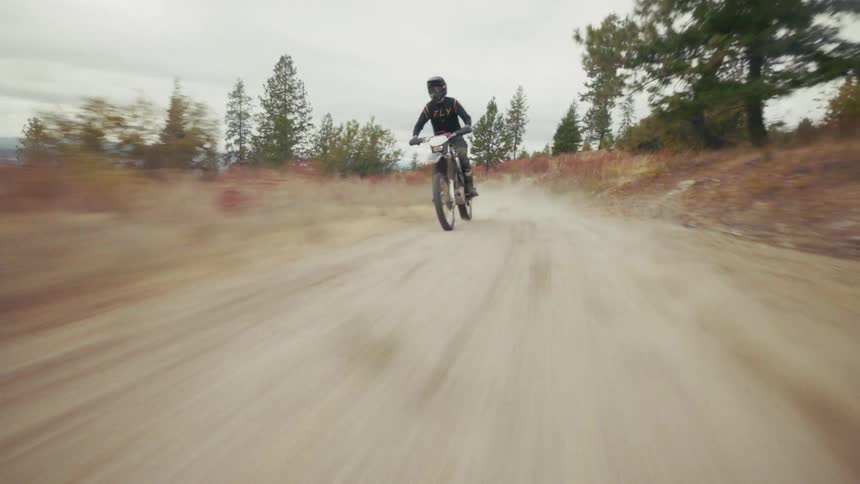 A man riding a mountain bike through the wilderness at midday wearing a helmet