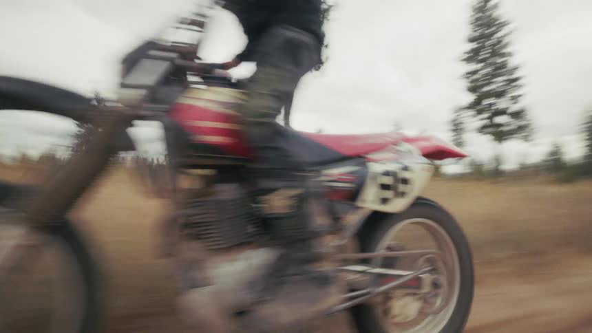 Cyclist riding a motorbike on a rural dirt road