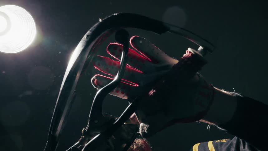 Thick black curved metal bar that arches over the riders hand it creates a strong semicircular silhouette against the dark background highlighted by the lens flare from the overhead light this line appears to be a protective handguard or a structu