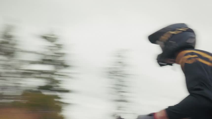 A rider in gear approaches their dirt bike on a sundrenched dusty trail while brilliant light rays filter through the treesa second motorcyclist in fly racing gear speeds along a dirt path through an open hilly landscape under a cloudy sky