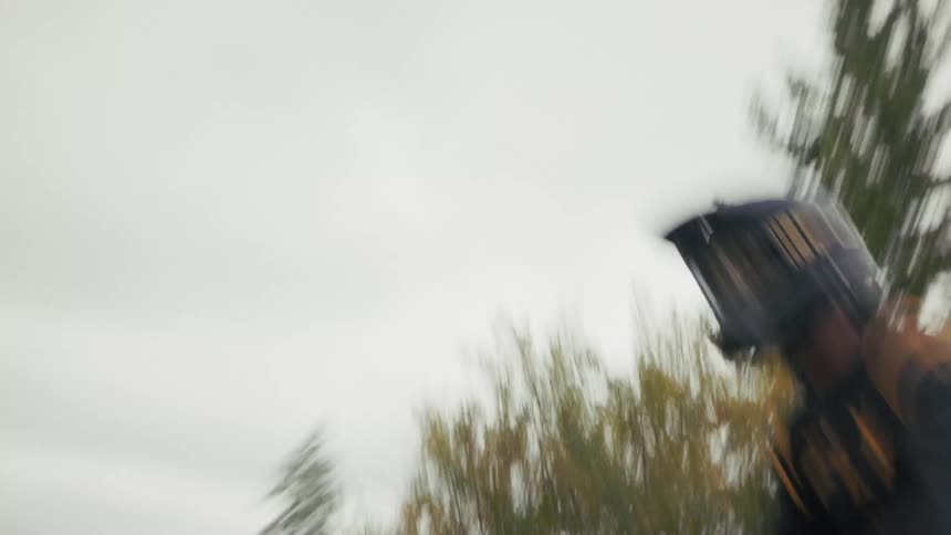 Motocross rider accelerating on a dirt trail with dust being kicked up in a wooded area