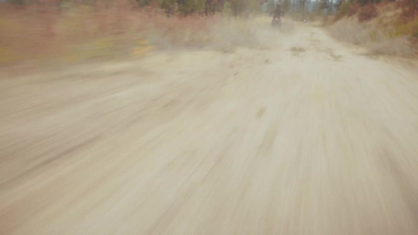 Dirt trail with dust rising from fast motorcycle movement in an open area