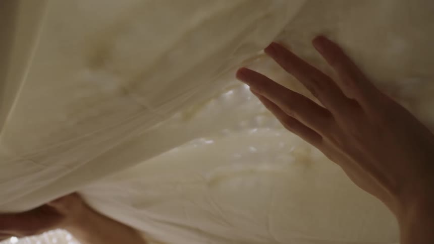 A woman rubs her hands on lace sheets