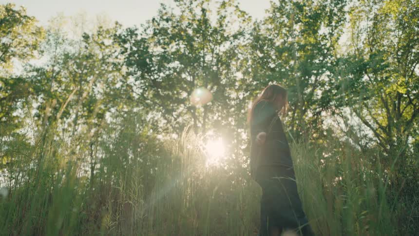 A woman walking out in a forest on a sunny day