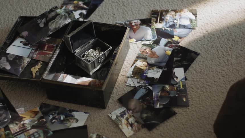 Person walking back and forth near pile of photos on carpet floor