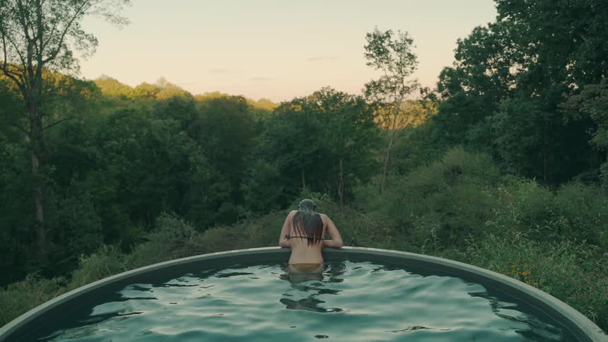 Female wearing a swimsuit on a swimming pool surrounded by trees outdoors during day time