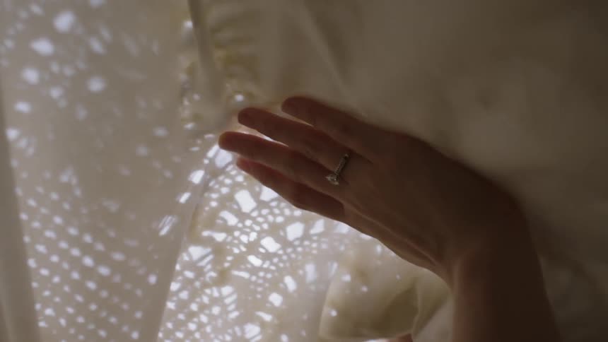A woman rubs her hands on lace sheets