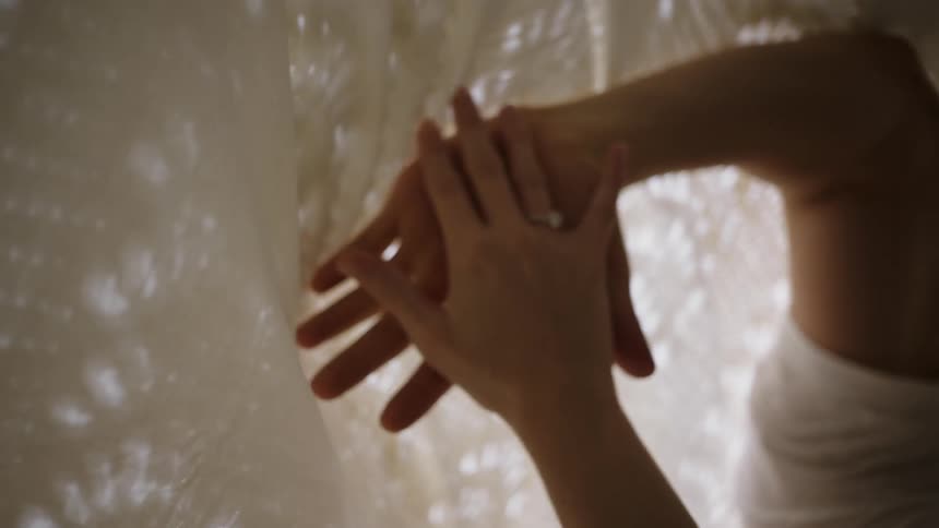 A woman rubs her hands on lace sheets