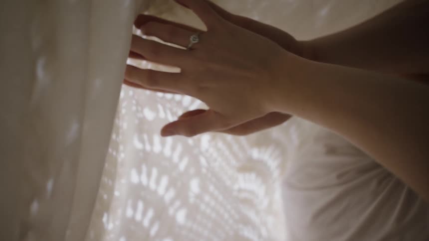 Two people hold hands under the blanket