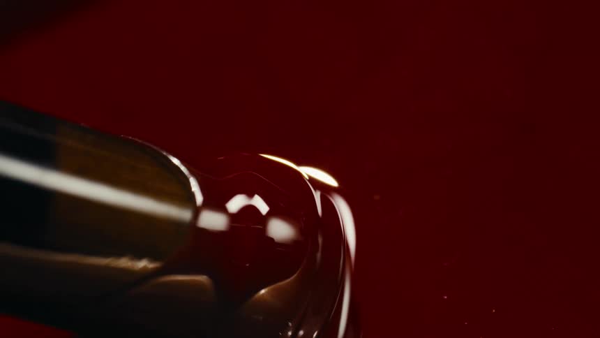 A red wine cork dipped into red sealant paint with paint dripping off as its lifted away
