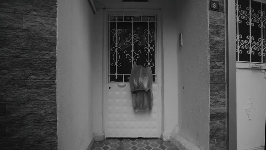 Plastic bags hanging from the door of an apartment building outdoors during day time