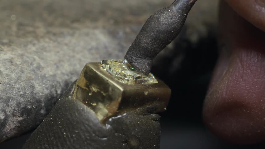Closeup hand of a jeweler using a tool on a piece of metal