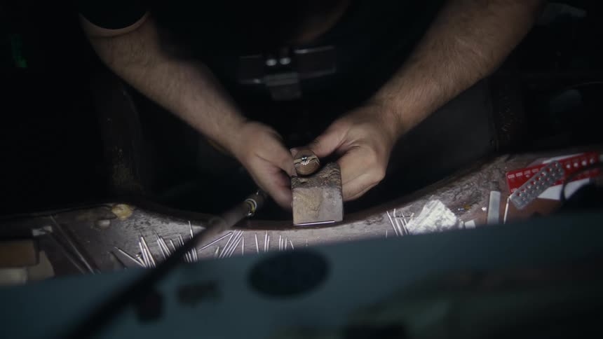 Hands of a jeweler working in a dark room