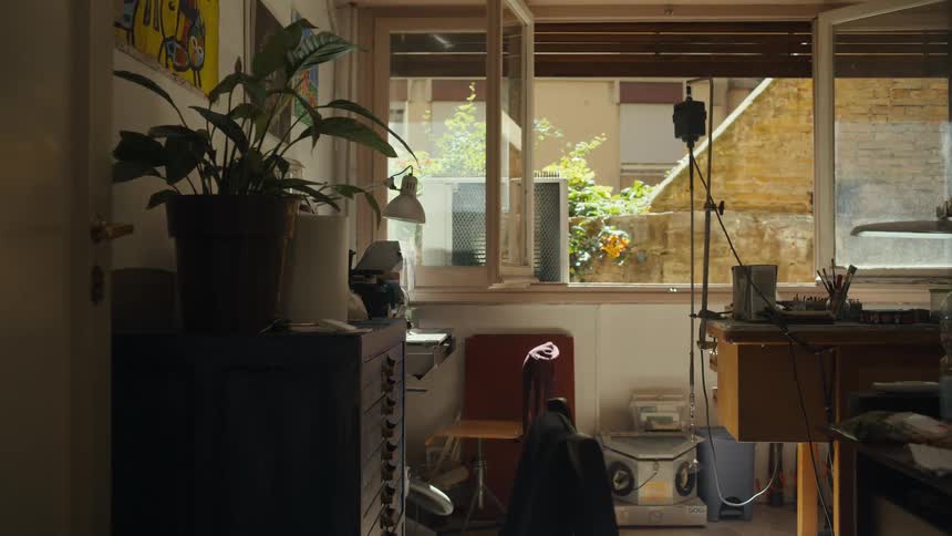 Studio lit by natural light shows creative space with plants art and recording equipment