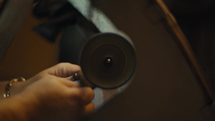 Metal object polished against rotating wheel in lowlight setting