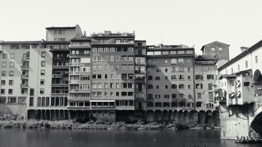 Row of historic buildings aligned along a riverbank in an urban area