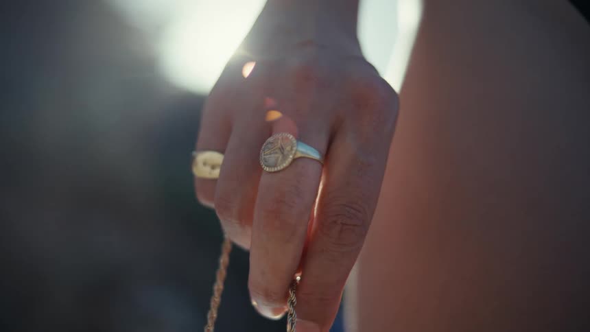 Hand holds metal chain with two distinct rings under soft light and blurred background