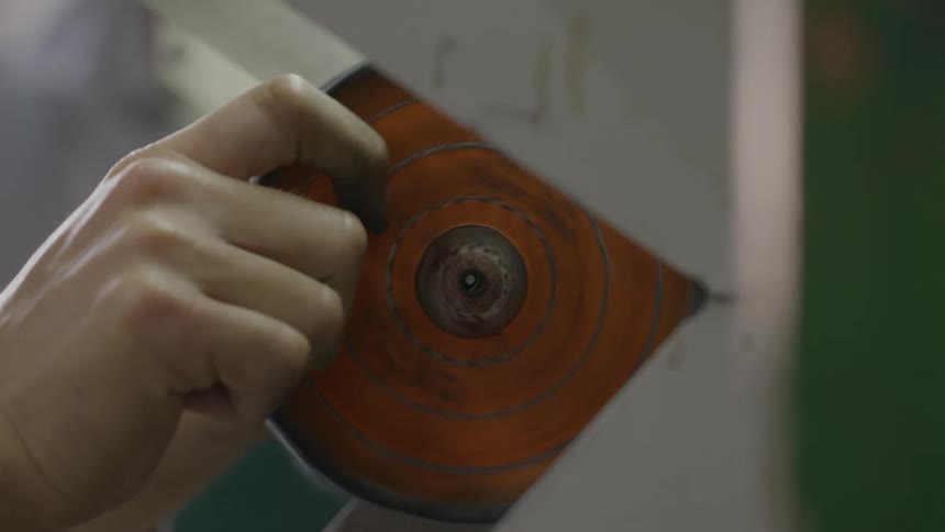 Technician is working with industrial equipment to maintain or adjust specialized components a workers hand carefully removes a circular orange and blue disc from a spinning rotary machineafter the disc is removed the person prepares to swap or clea