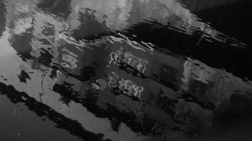 Water surface with ripples reflecting light and dark shapes
