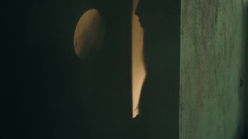 A woman enters a door into a dark room