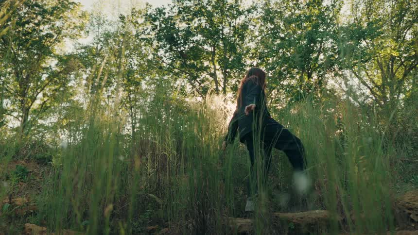 A woman walking through a forest on a sunny day