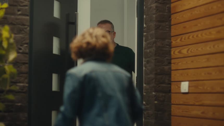 A man gives a bouquet of roses to a woman at a doorway before her father appears and usher her inside