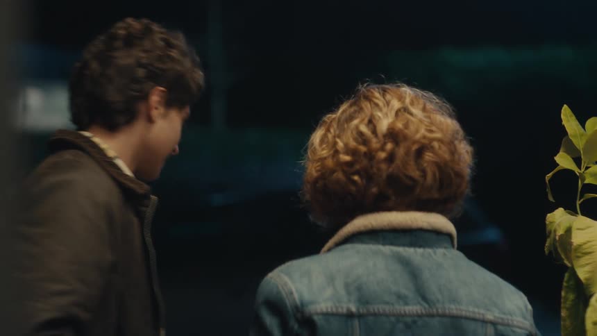 The man gives flowers to his date and they hug
