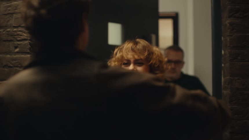 Father opens the door and greets his soninlaw with his daughter embracing him at night