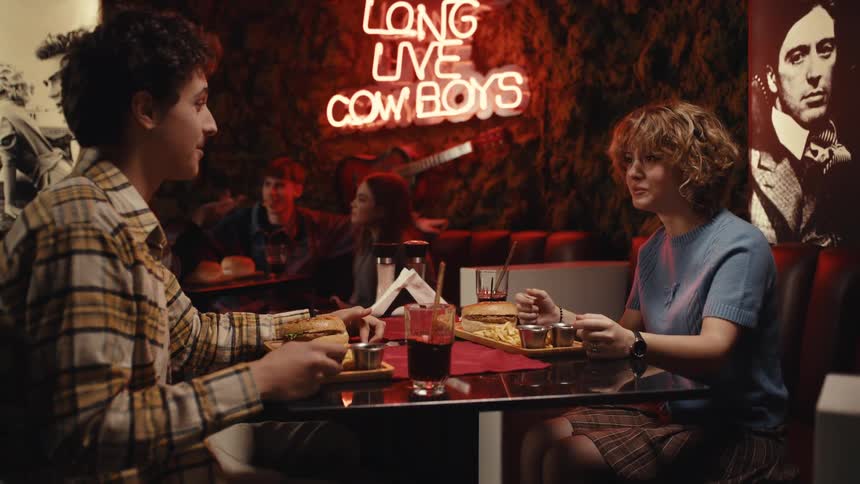 A couple enjoys a romantic dinner date at a small table in a dimly lit restaurant