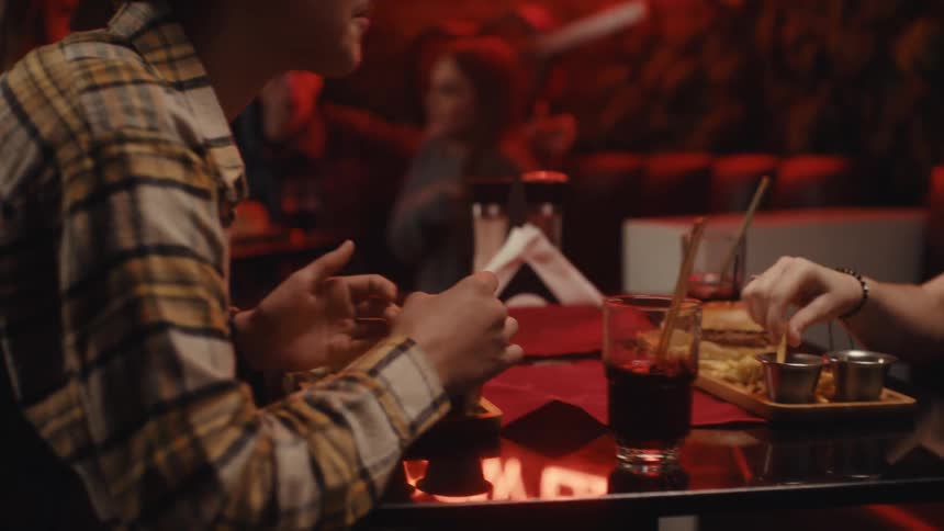 Couple seated at a table in an indoor setting with warm lighting with drinks and food placed on the surface