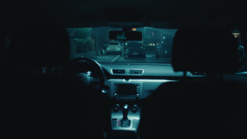 Two people getting out of a car at night and walking towards the door of a house