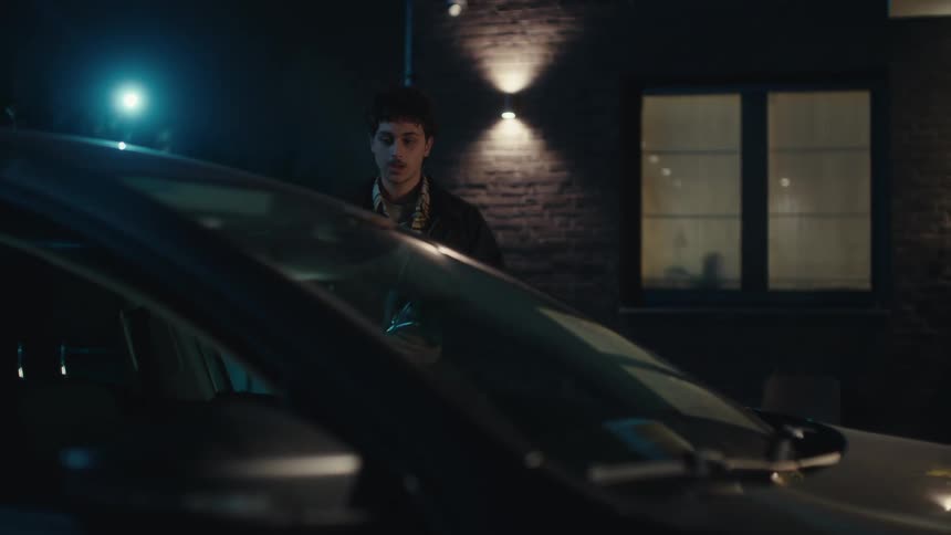 A man holding a bouquet of red roses gets out of a car and walks toward the front door of a house at night