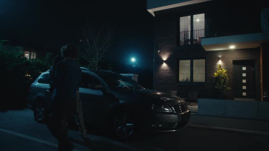 Couple of male and female teenagers leaving a house and walking through the street to get into a car while holding hands in a suburban neighborhood outdoors during night time