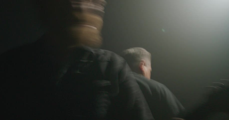 The neck and headstock of the electric guitar which create a sharp diagonal line across the frame as the musician movesthe bright linear shafts of light cutting through the smoky atmosphere forming a highcontrast backlighting effect