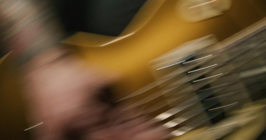 A close view shows a musicians hands rapidly playing an electric guitar