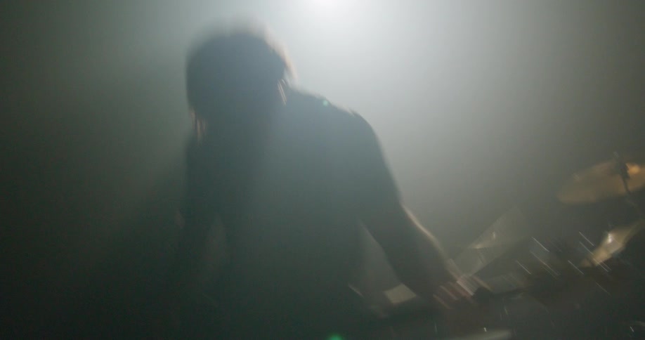 Bass player on a stage playing next to a drummer at a concert