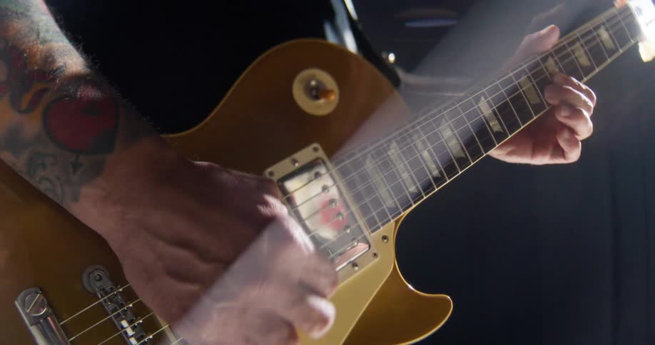 A man with tattoos is playing an electric guitar