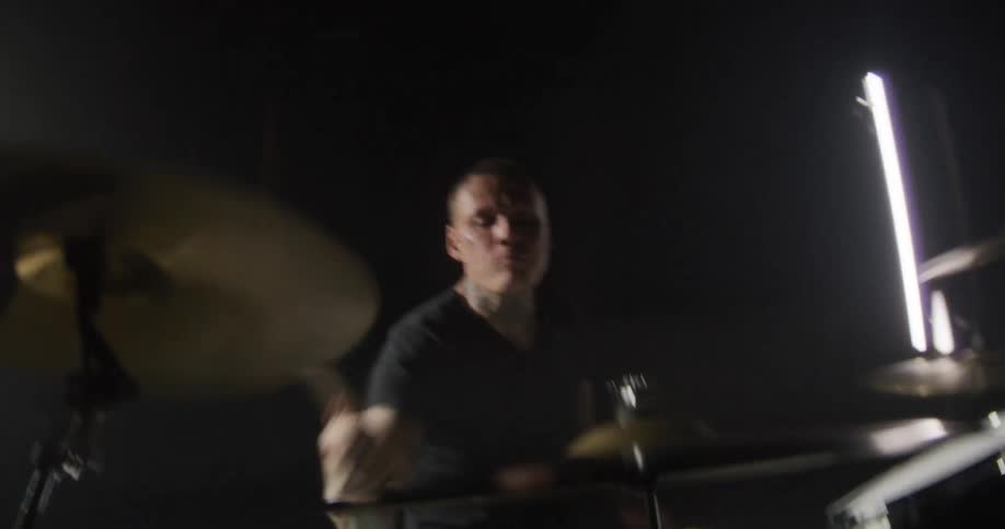 Man holds his drum sticks and swings his arms as he plays the drums