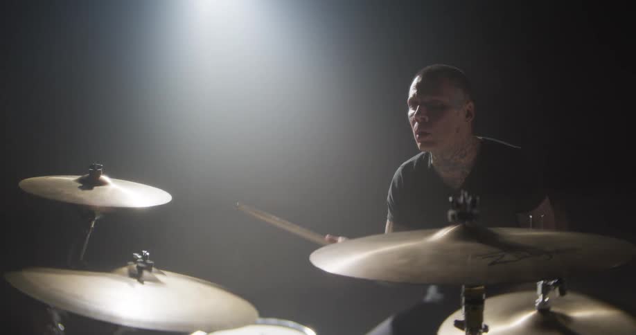 Man holds his drum sticks and swings his arms as he plays the drums