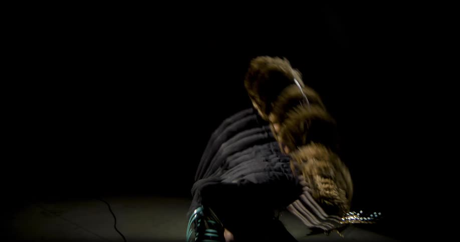 Guitarist playing with intense movement in a dark studio