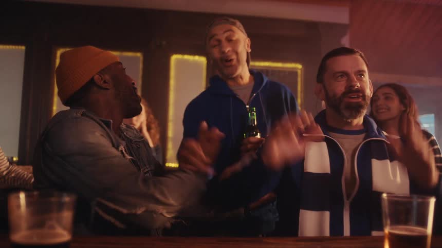 Group of people celebrating in a bar with drinks on the counter