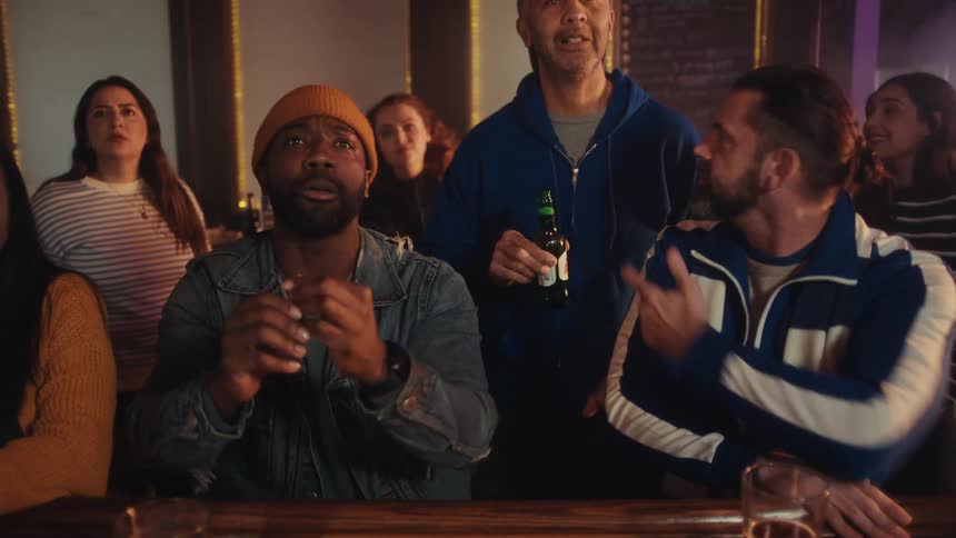 People sitting in a bar watching a sports game on television